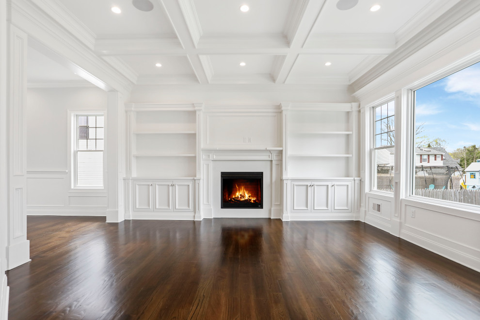 Inspiration for a mid-sized timeless open concept medium tone wood floor, brown floor, coffered ceiling and wainscoting living room remodel in New York with white walls, a standard fireplace, a wood fireplace surround and a wall-mounted tv