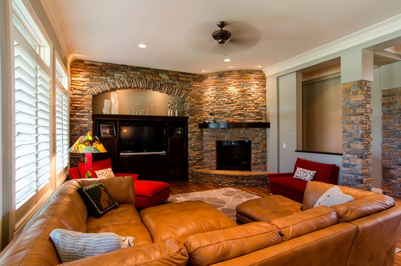 Example of a large classic open concept medium tone wood floor living room design in Other with beige walls, a standard fireplace, a stone fireplace and a media wall