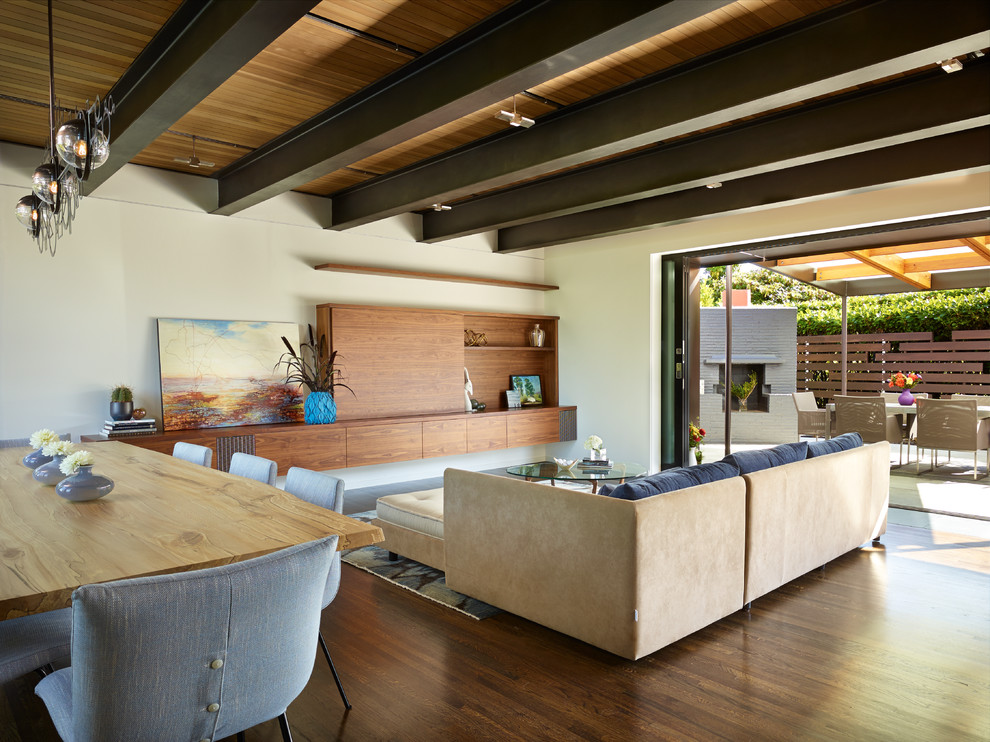 Diseño de salón abierto retro grande con paredes blancas, suelo de madera en tonos medios y televisor retractable