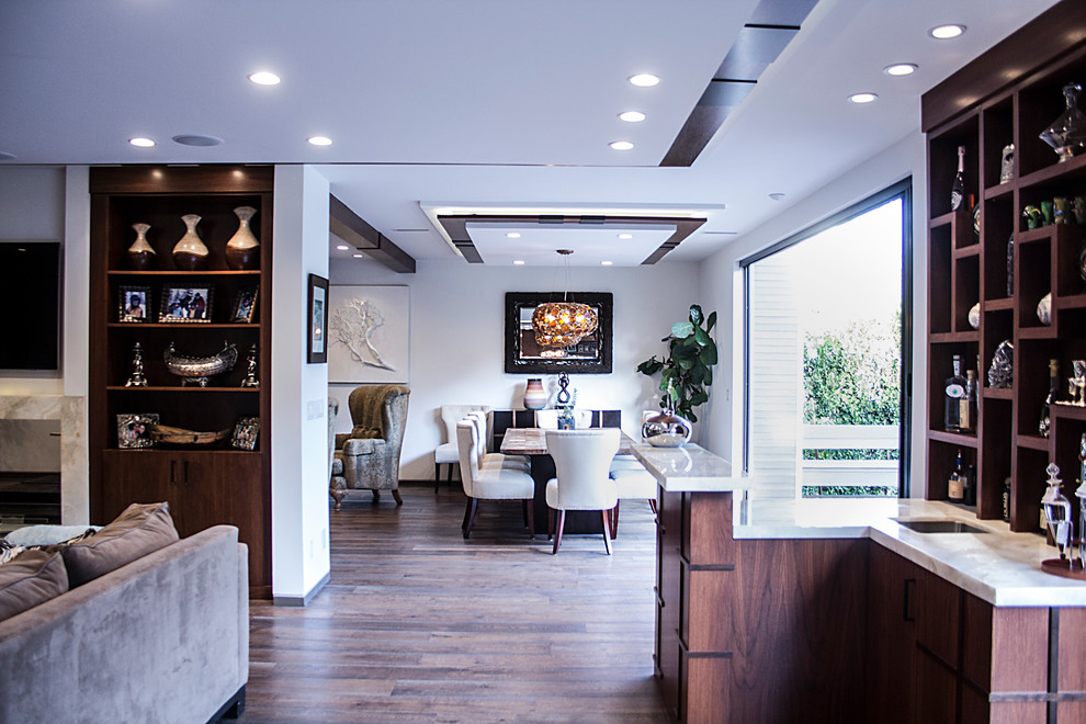 Пример оригинального дизайна: открытая гостиная комната среднего размера в стиле модернизм с домашним баром, белыми стенами, светлым паркетным полом, двусторонним камином, фасадом камина из камня и телевизором на стене