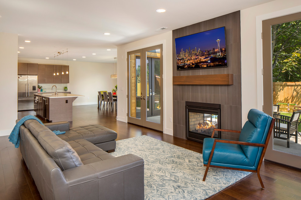 Photo of a large contemporary open plan living room in Seattle with beige walls, dark hardwood flooring, a two-sided fireplace, a tiled fireplace surround and a wall mounted tv.