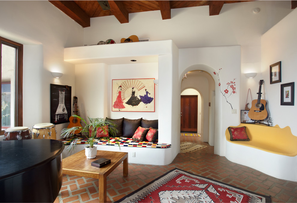 На фото: открытая гостиная комната в стиле фьюжн с белыми стенами, кирпичным полом, угловым камином, фасадом камина из штукатурки, красным полом и балками на потолке