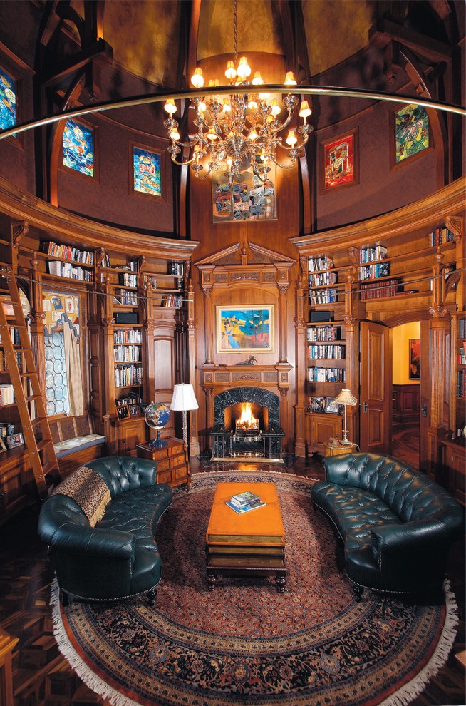 Cette photo montre un grand salon craftsman fermé avec une bibliothèque ou un coin lecture, un mur marron, une cheminée standard, un manteau de cheminée en bois, aucun téléviseur et éclairage.