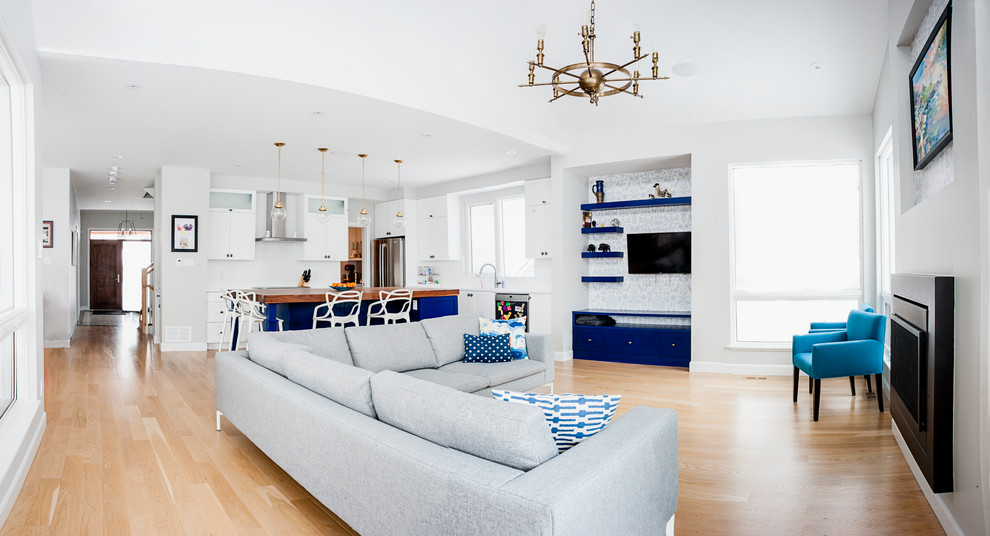Offenes Modernes Wohnzimmer mit weißer Wandfarbe, hellem Holzboden, TV-Wand, Kamin und Kaminumrandung aus Metall in Ottawa