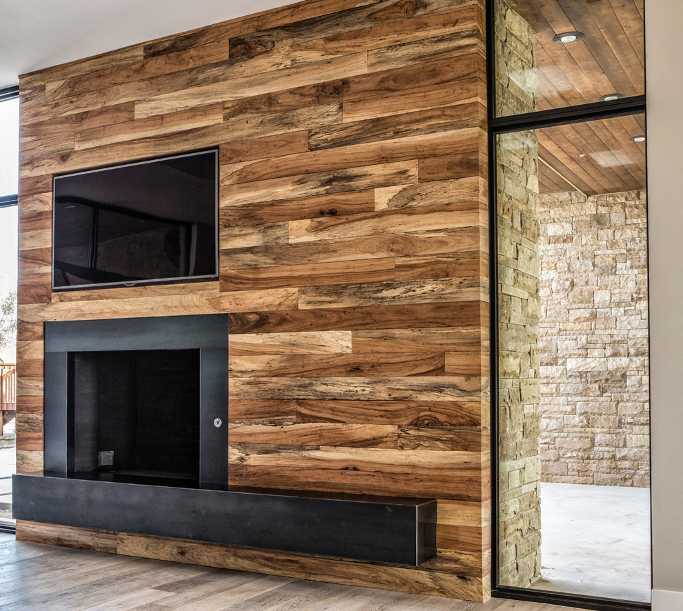 Großes, Offenes Modernes Wohnzimmer mit bunten Wänden, braunem Holzboden, Kamin, Kaminumrandung aus Holz und TV-Wand in Austin