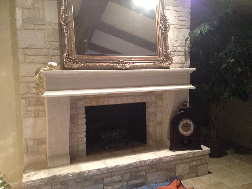 オースティンにある広いトラディショナルスタイルのおしゃれなリビング (ベージュの壁、トラバーチンの床、標準型暖炉、石材の暖炉まわり) の写真