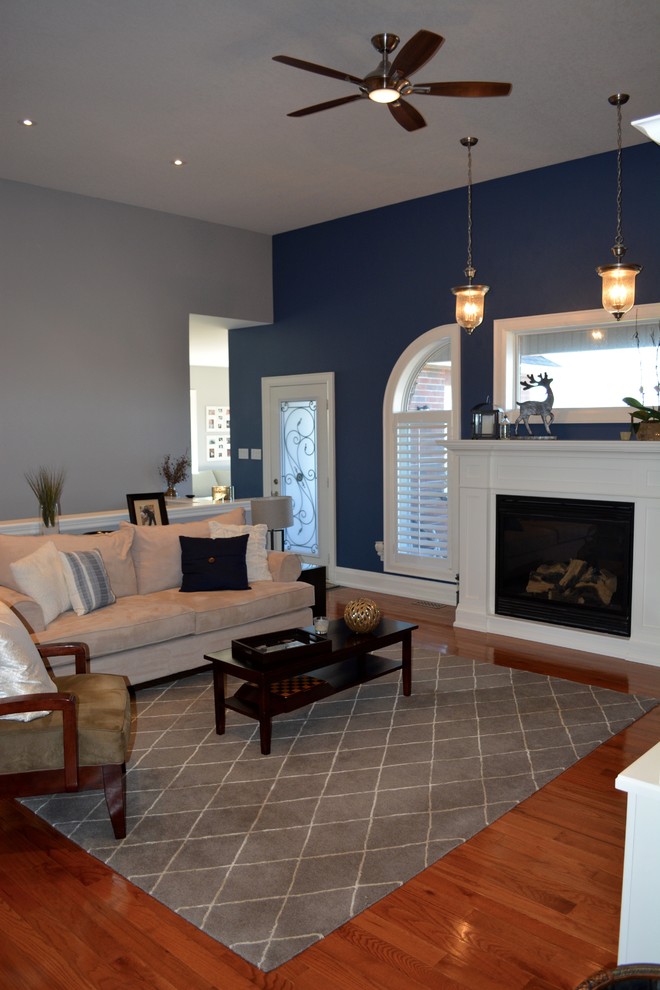 Inspiration for a medium sized traditional open plan living room in Toronto with blue walls, light hardwood flooring, a standard fireplace and a wooden fireplace surround.
