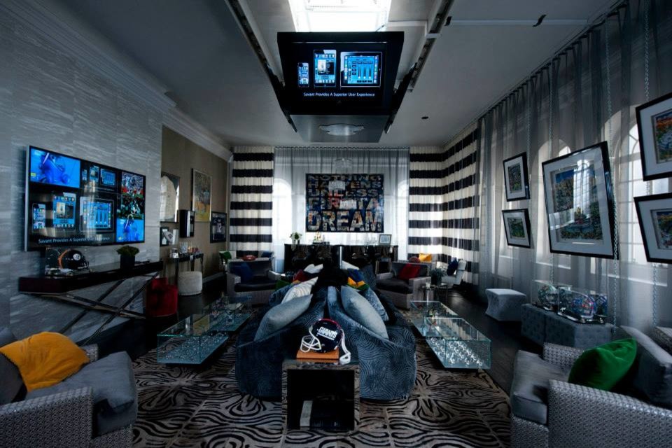 Immagine di un grande soggiorno design aperto con TV a parete, pareti grigie e parquet scuro
