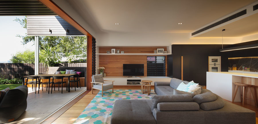 Réalisation d'un salon design ouvert avec un mur noir, un sol en bois brun et un téléviseur indépendant.