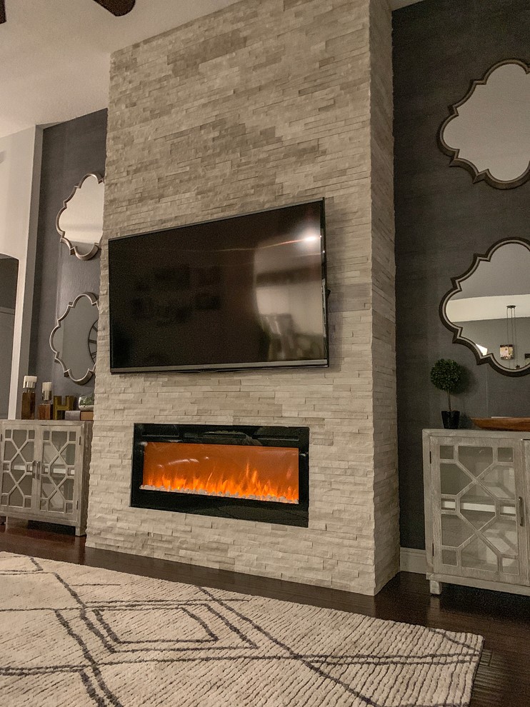 オーランドにあるお手頃価格の広いラスティックスタイルのおしゃれなLDK (グレーの壁、濃色無垢フローリング、石材の暖炉まわり、壁掛け型テレビ、茶色い床、横長型暖炉) の写真