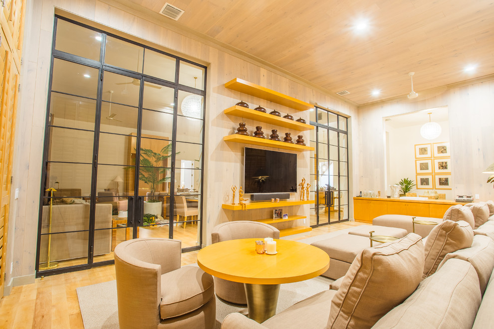 Ejemplo de salón abierto tradicional renovado grande sin chimenea con paredes beige, suelo de madera clara, televisor colgado en la pared y suelo beige
