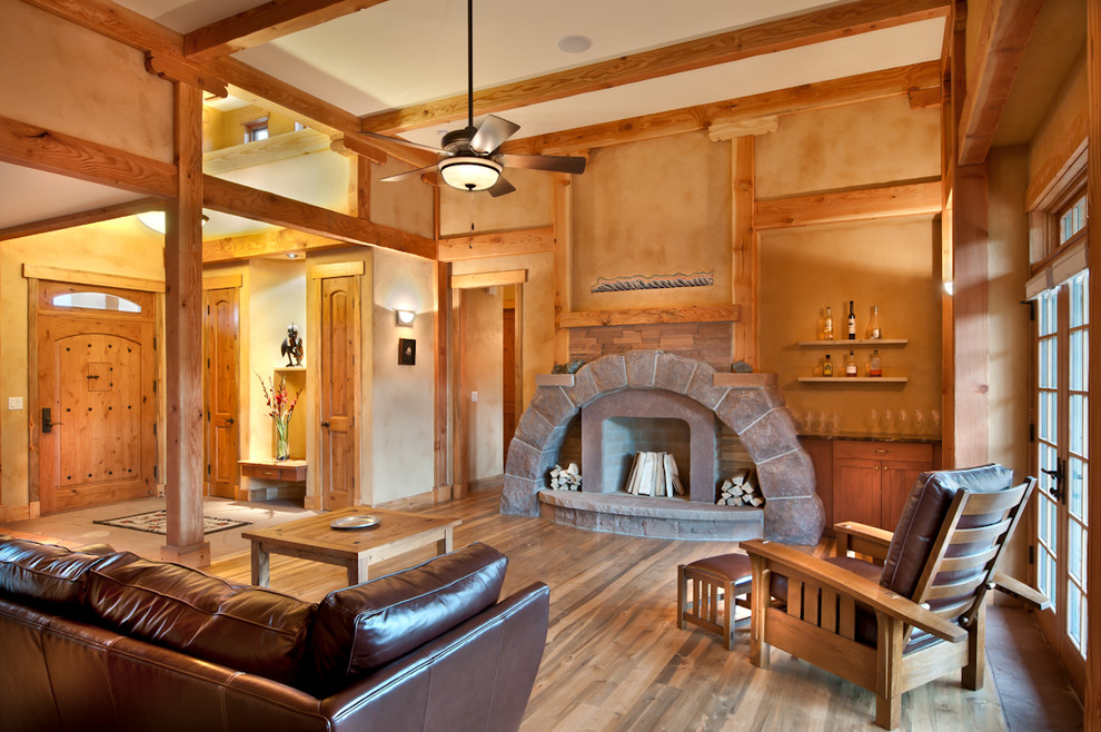 Mediterranes Wohnzimmer mit beiger Wandfarbe, dunklem Holzboden und Kaminumrandung aus Stein in Denver