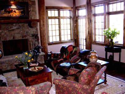 Foto di un grande soggiorno rustico aperto con sala formale, pareti beige, parquet scuro, camino classico, cornice del camino in pietra e nessuna TV