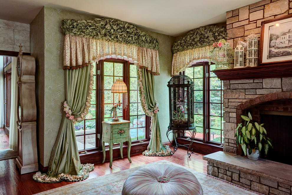 Exemple d'un grand salon chic fermé avec une salle de réception, un mur vert, un sol en bois brun, une cheminée standard, un manteau de cheminée en pierre et aucun téléviseur.