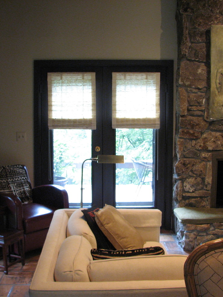 На фото: парадная, изолированная гостиная комната среднего размера в стиле рустика с белыми стенами, полом из терракотовой плитки, стандартным камином, фасадом камина из камня и коричневым полом без телевизора