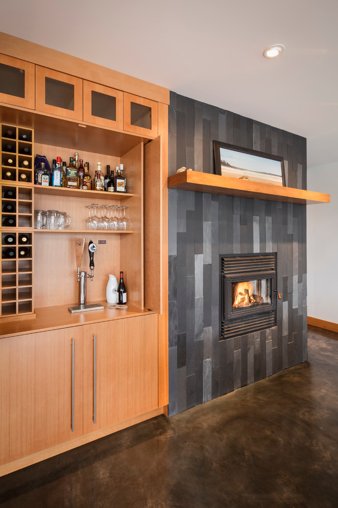 Modelo de salón con barra de bar contemporáneo con suelo de cemento y marco de chimenea de baldosas y/o azulejos