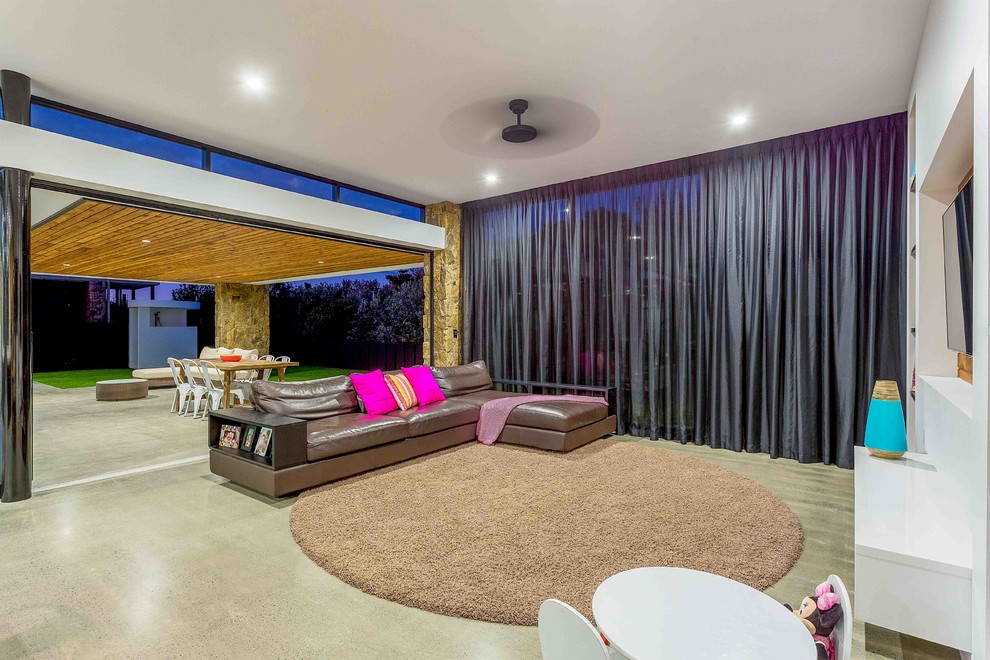 This is an example of a contemporary open plan living room in Gold Coast - Tweed with white walls, concrete flooring, a wall mounted tv and grey floors.