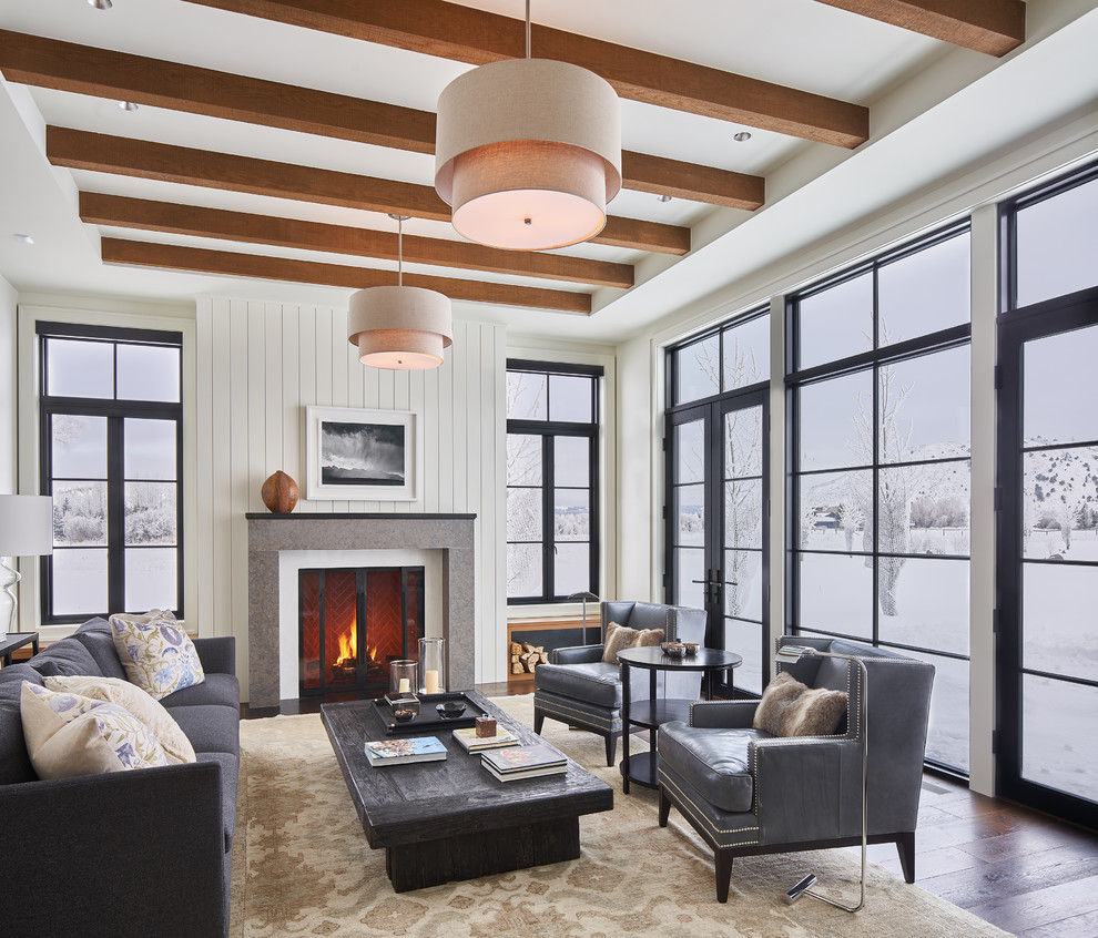 Imagen de salón campestre con paredes blancas, suelo de madera en tonos medios, todas las chimeneas y suelo marrón