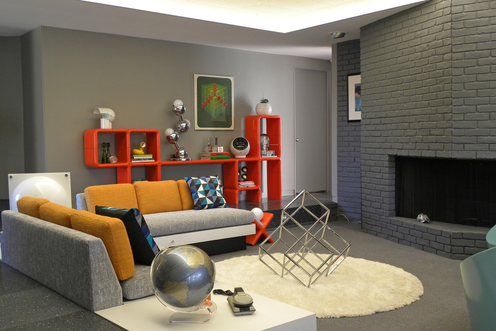 Inspiration pour un salon vintage avec un manteau de cheminée en brique, une cheminée d'angle et un mur gris.