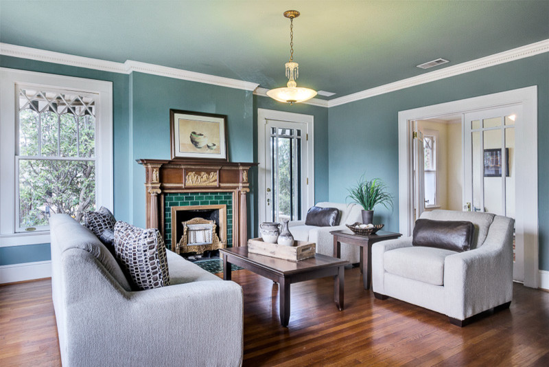 Esempio di un soggiorno stile americano chiuso con pareti blu, pavimento in legno massello medio, camino classico, cornice del camino piastrellata e nessuna TV