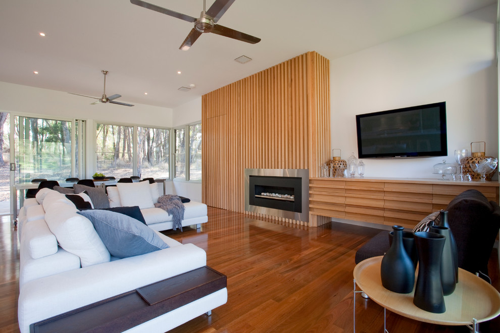 Cette photo montre un salon tendance ouvert avec une salle de réception, un mur blanc, un sol en bois brun, une cheminée standard, un manteau de cheminée en métal et un téléviseur fixé au mur.