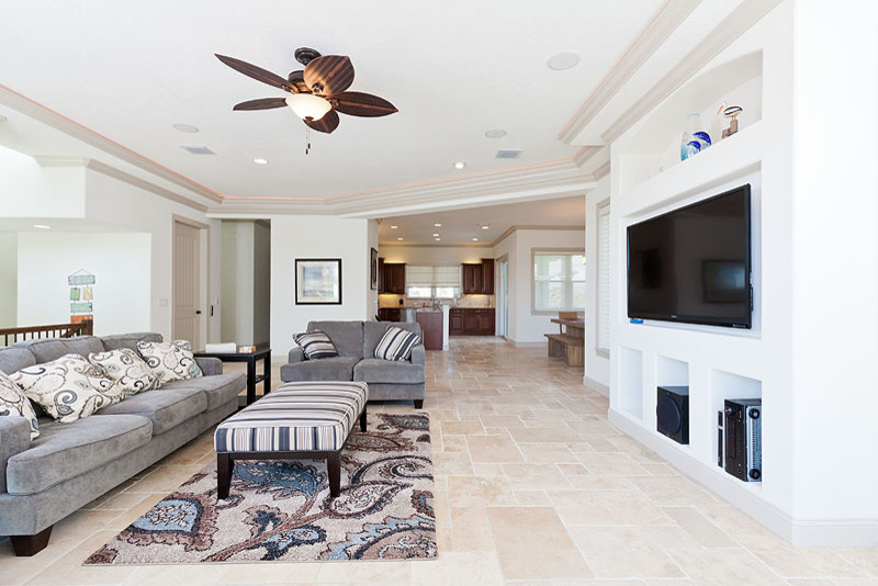 Living room - large coastal formal and open concept travertine floor living room idea in Orlando with white walls and a media wall