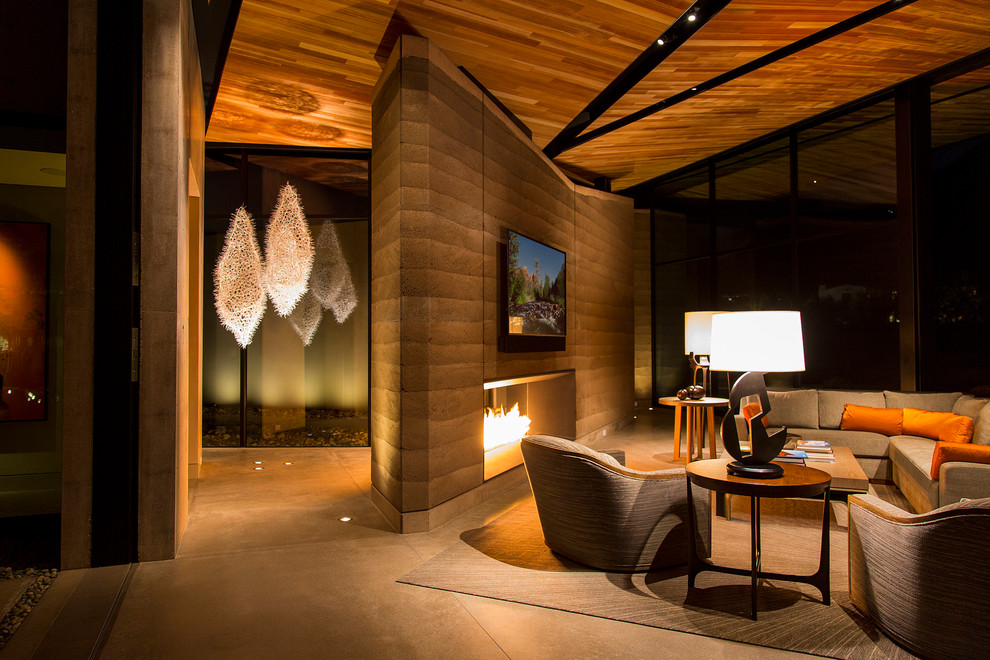 フェニックスにある高級な広いサンタフェスタイルのおしゃれなリビング (茶色い壁、吊り下げ式暖炉、壁掛け型テレビ) の写真
