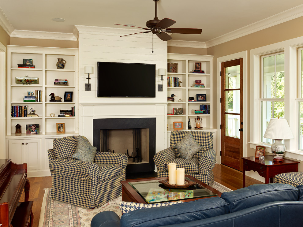 Mittelgroßes, Abgetrenntes Klassisches Wohnzimmer mit Kamin, TV-Wand, beiger Wandfarbe, braunem Holzboden, verputzter Kaminumrandung und beigem Boden in Charleston