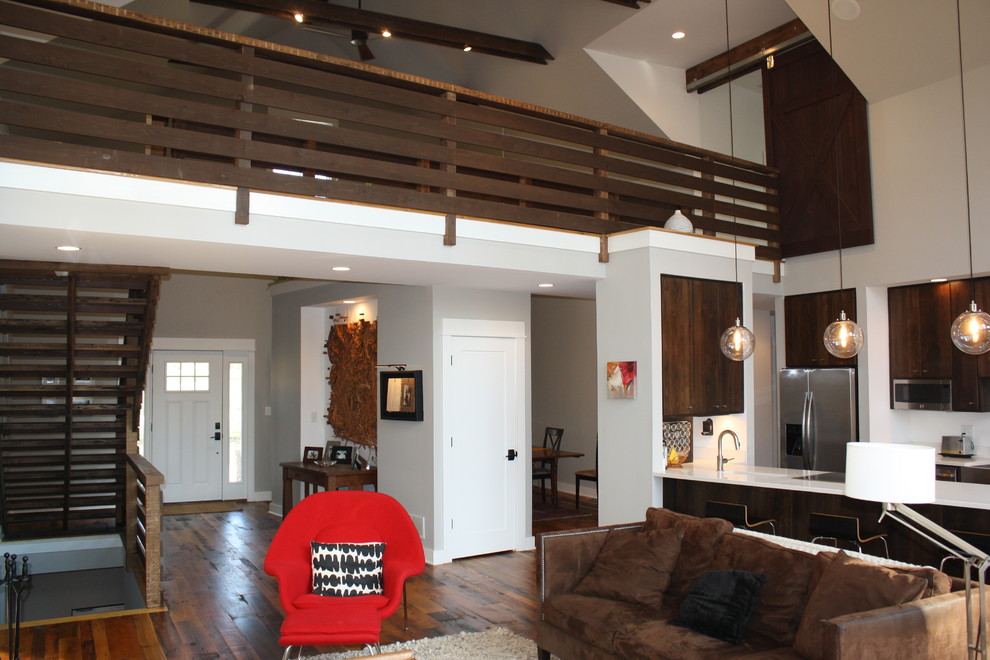 Пример оригинального дизайна: парадная, двухуровневая гостиная комната среднего размера в стиле кантри с серыми стенами, паркетным полом среднего тона, стандартным камином, фасадом камина из дерева и телевизором на стене