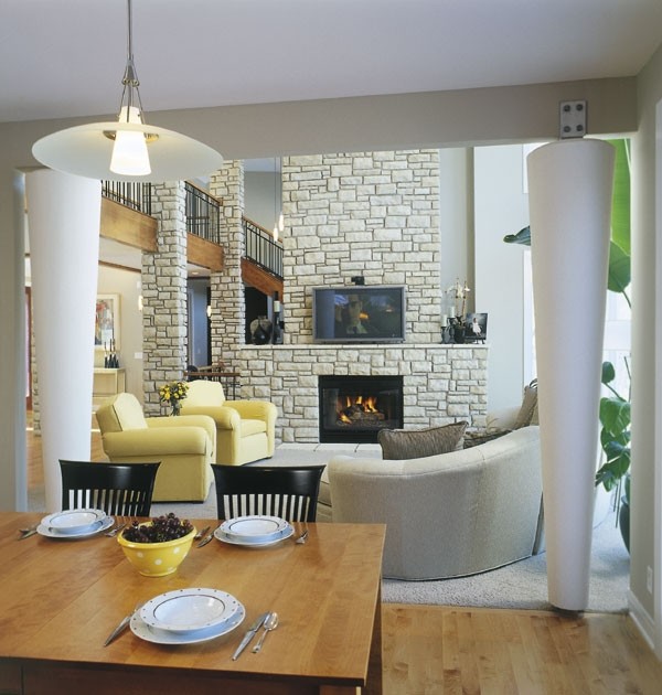 Idée de décoration pour un grand salon tradition ouvert avec un sol en bois brun, une cheminée standard, un manteau de cheminée en pierre et un téléviseur fixé au mur.