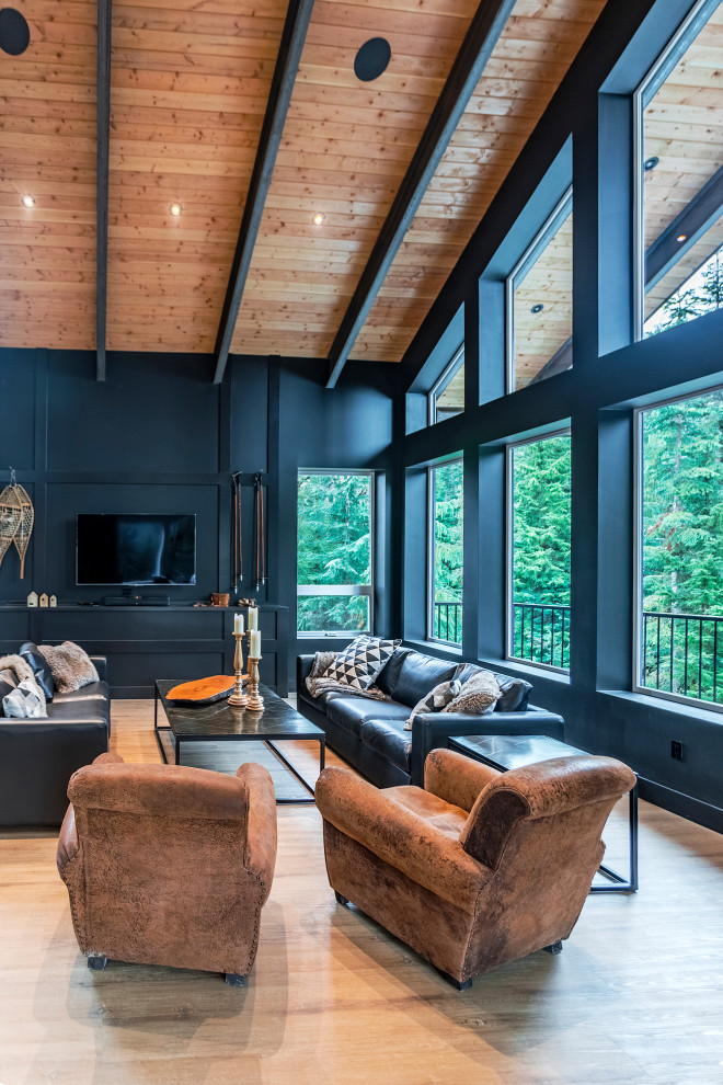 Geräumiges, Offenes Modernes Wohnzimmer mit schwarzer Wandfarbe, Vinylboden, Kaminofen, freistehendem TV und braunem Boden in Vancouver