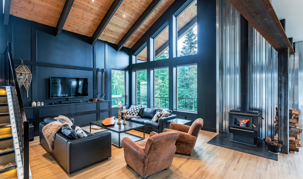 Design ideas for an expansive modern open plan living room in Vancouver with vinyl flooring, a wood burning stove, brown floors, black walls and a freestanding tv.