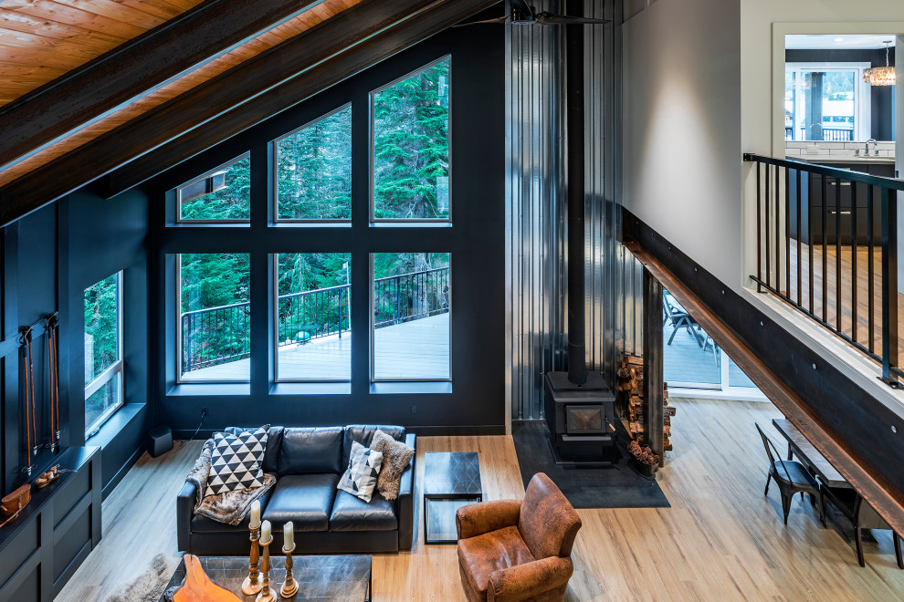 Esempio di un ampio soggiorno moderno aperto con pareti nere, pavimento in vinile, stufa a legna, cornice del camino in metallo, TV autoportante e pavimento marrone