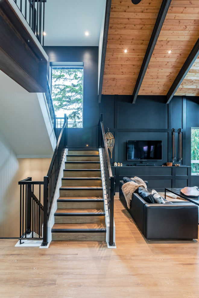 Foto di un ampio soggiorno minimalista aperto con pareti nere, pavimento in vinile, stufa a legna, TV autoportante e pavimento marrone