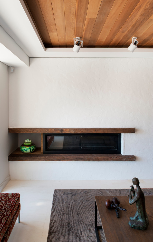 Diseño de salón actual de tamaño medio con paredes blancas, chimenea lineal y marco de chimenea de madera