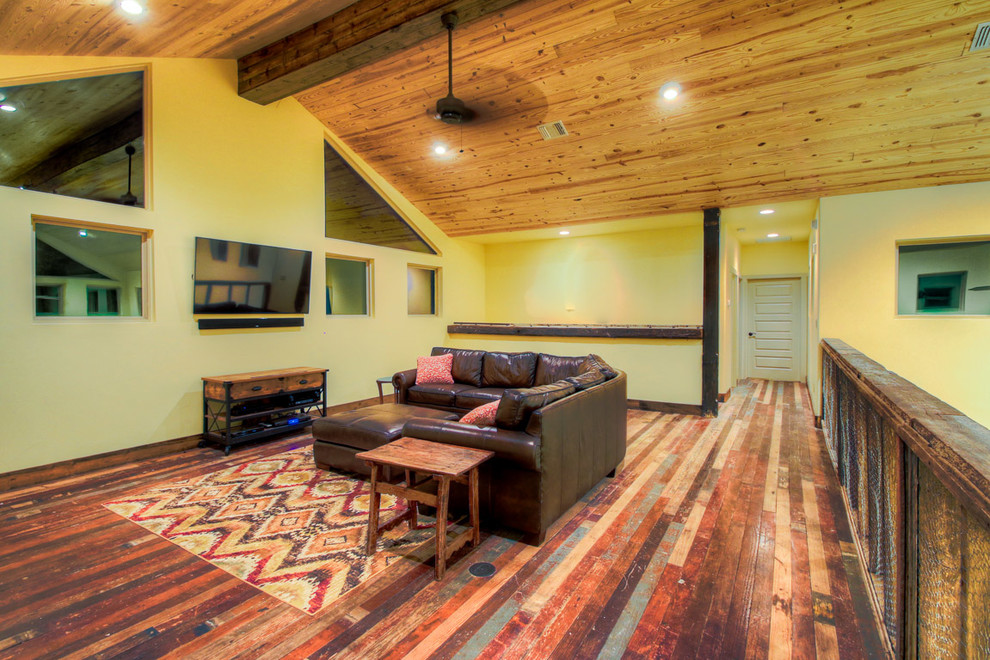 Großes, Offenes Uriges Wohnzimmer mit weißer Wandfarbe, dunklem Holzboden, Kamin, Kaminumrandung aus Stein und TV-Wand in Austin
