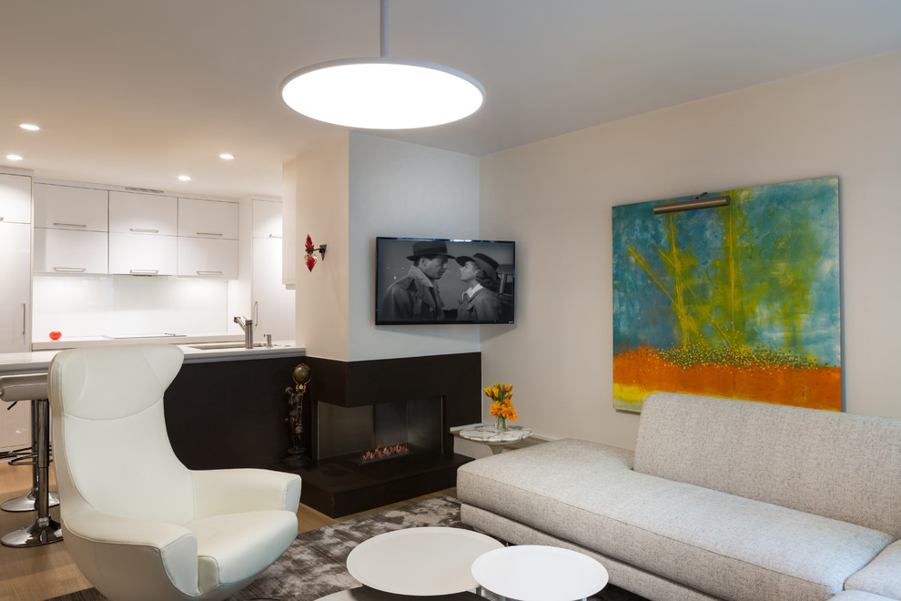 Esempio di un piccolo soggiorno minimal aperto con pareti bianche, parquet chiaro, camino ad angolo, cornice del camino piastrellata e TV a parete