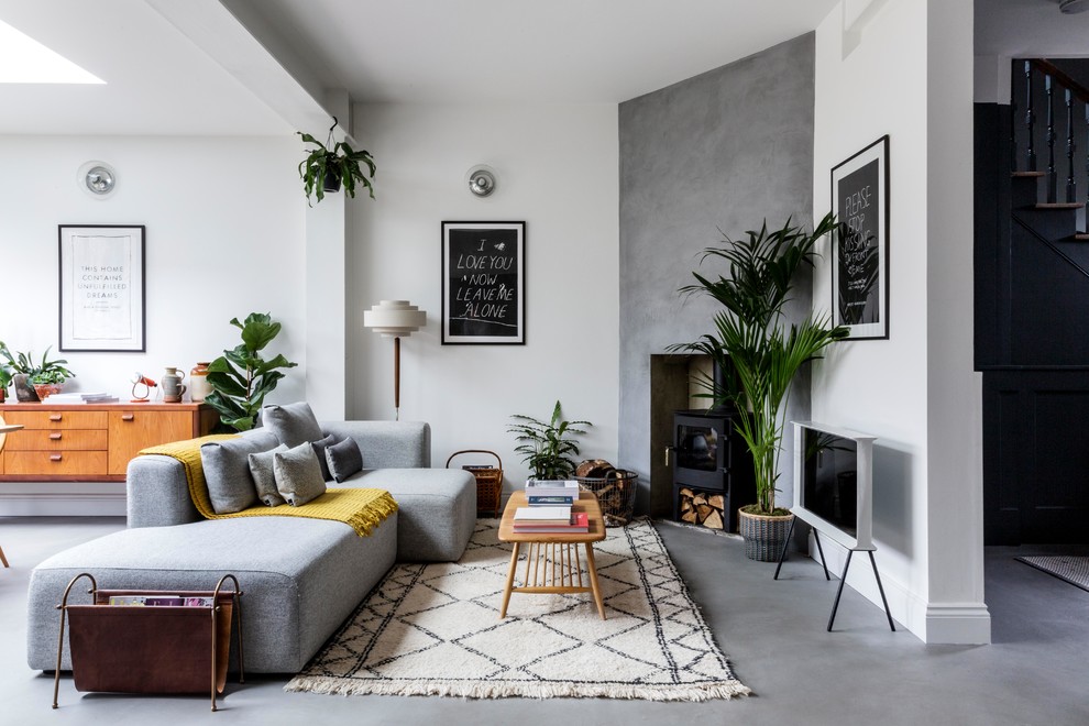 Inspiration for a mid-sized scandinavian open concept concrete floor and gray floor living room remodel in London with white walls, a wood stove and a tv stand