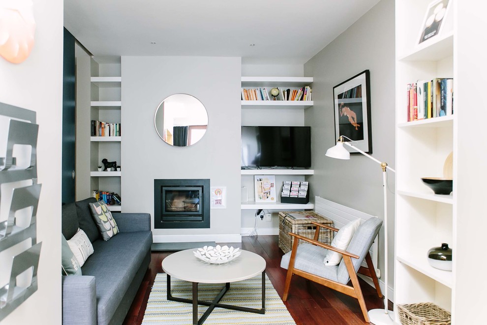 Inspiration för små minimalistiska separata vardagsrum, med vita väggar, mörkt trägolv, en öppen vedspis, en spiselkrans i metall och en fristående TV