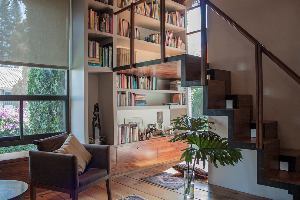 Modelo de biblioteca en casa contemporánea con suelo de madera en tonos medios