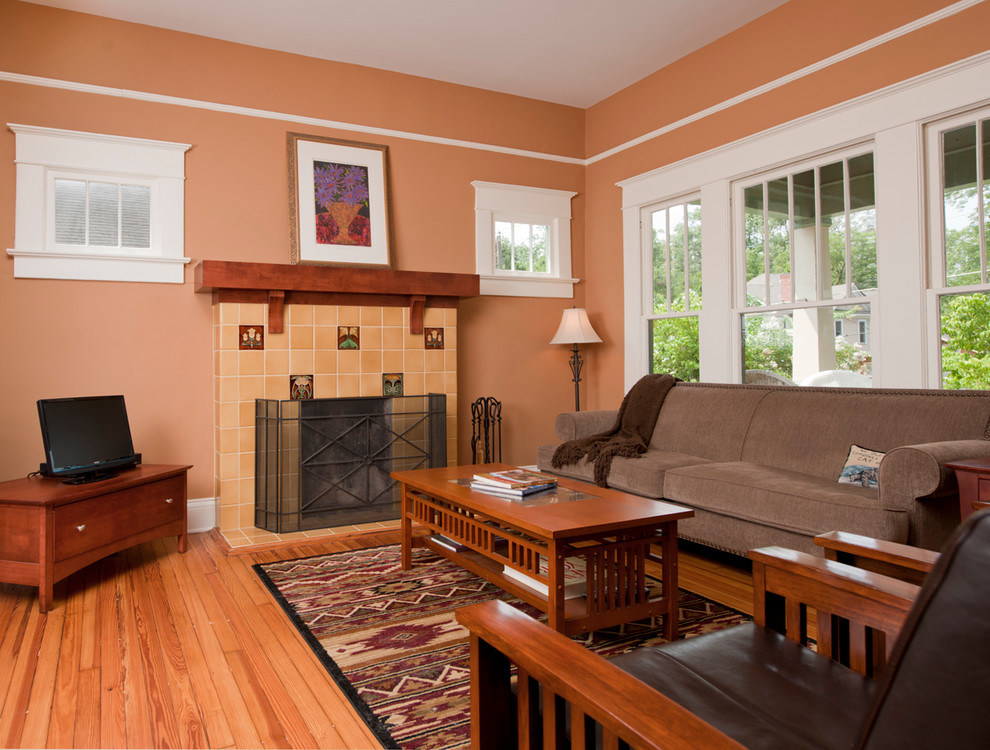 Foto på ett vintage vardagsrum, med orange väggar, mellanmörkt trägolv, en standard öppen spis, en spiselkrans i trä och en fristående TV
