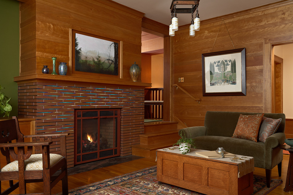 Inspiration för ett amerikanskt separat vardagsrum, med mellanmörkt trägolv, en standard öppen spis, en väggmonterad TV och bruna väggar