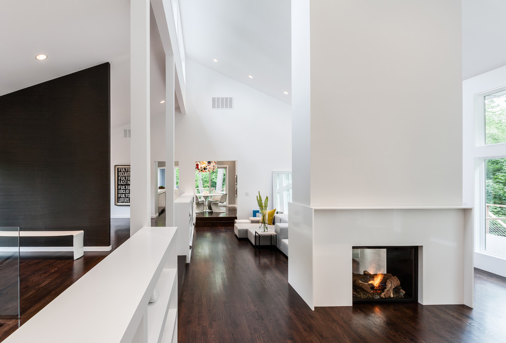 Пример оригинального дизайна: гостиная комната в стиле модернизм с белыми стенами и двусторонним камином