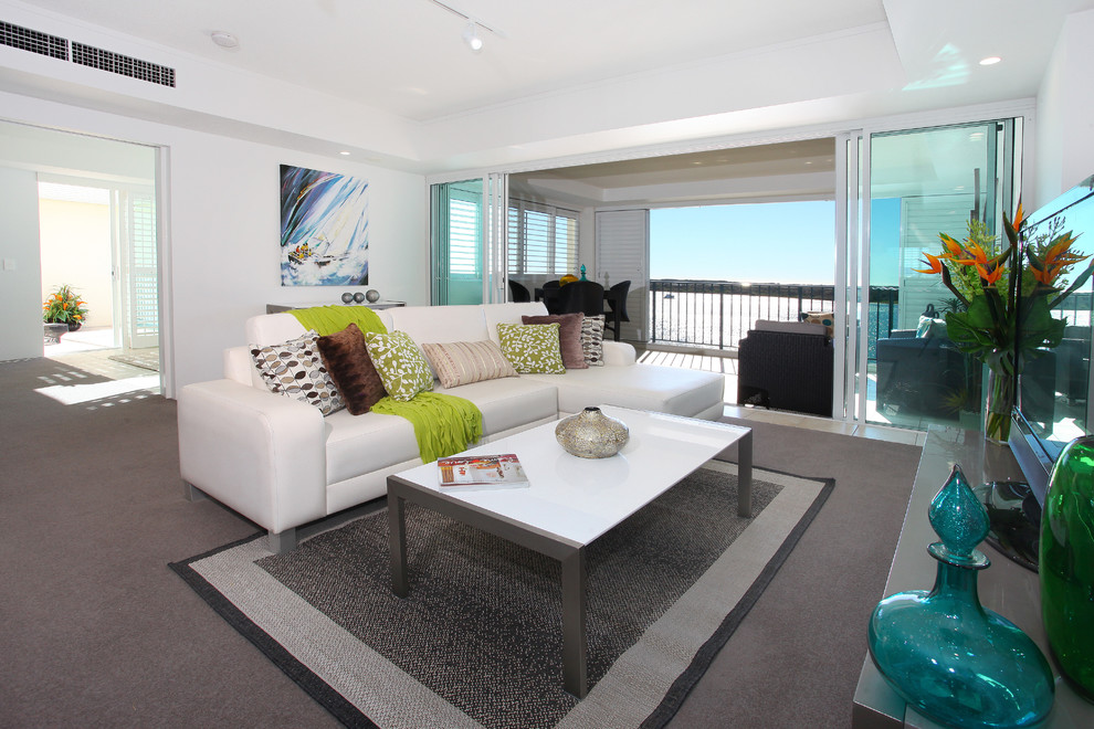 Ejemplo de salón abierto costero de tamaño medio con paredes blancas, moqueta y televisor independiente