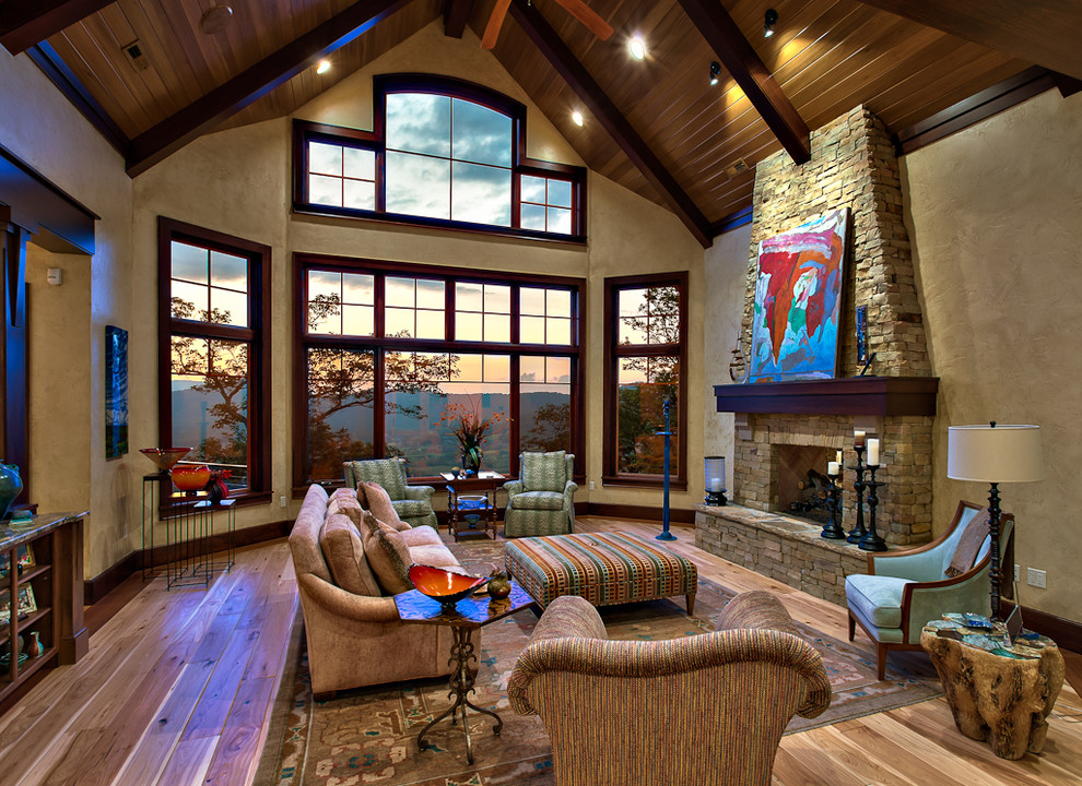 Large mountain style formal and open concept light wood floor, brown floor and exposed beam living room photo in Other with beige walls, a standard fireplace, a stone fireplace and no tv