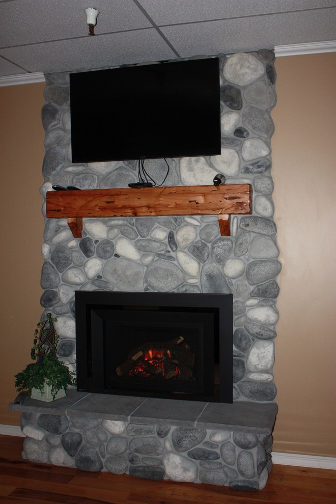 ソルトレイクシティにあるラスティックスタイルのおしゃれなリビング (ベージュの壁、無垢フローリング、標準型暖炉、石材の暖炉まわり、壁掛け型テレビ) の写真