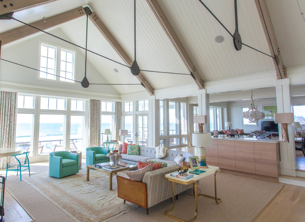 Exemple d'un grand salon bord de mer ouvert avec parquet clair, un mur blanc, un sol marron et une cheminée standard.