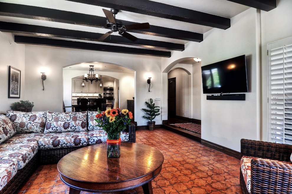 Large tuscan enclosed terra-cotta tile and brown floor living room photo in Orange County with white walls, no fireplace and a wall-mounted tv