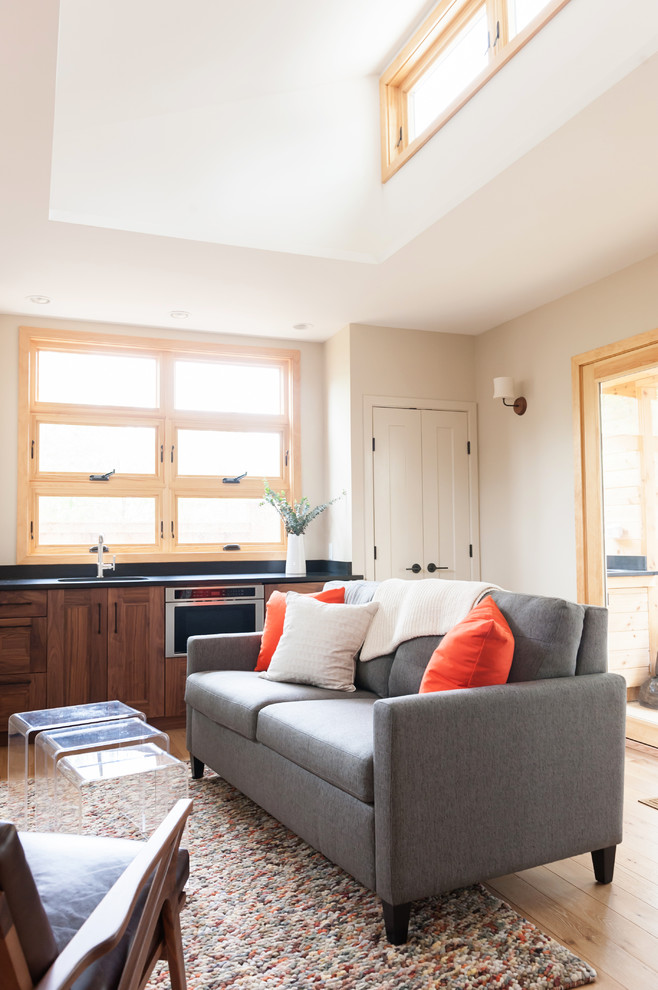 Ejemplo de salón abierto minimalista pequeño con paredes beige, suelo de madera clara, televisor colgado en la pared y suelo beige