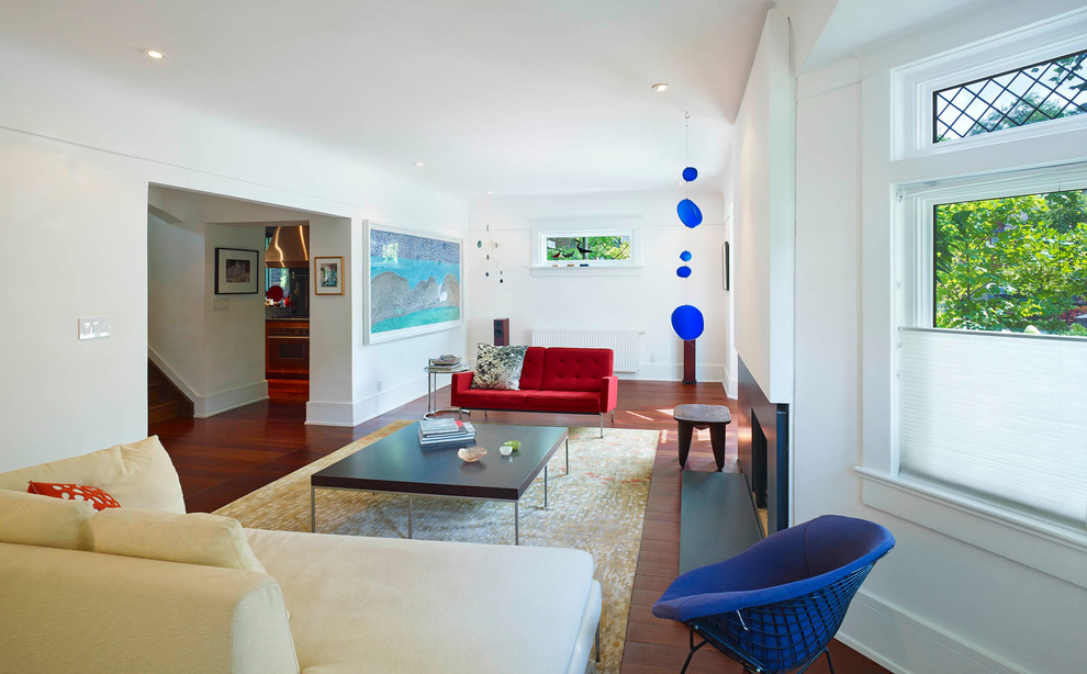 Mittelgroßes, Abgetrenntes, Fernseherloses Modernes Wohnzimmer mit weißer Wandfarbe, braunem Holzboden, Kamin, Kaminumrandung aus Stein und braunem Boden in Toronto